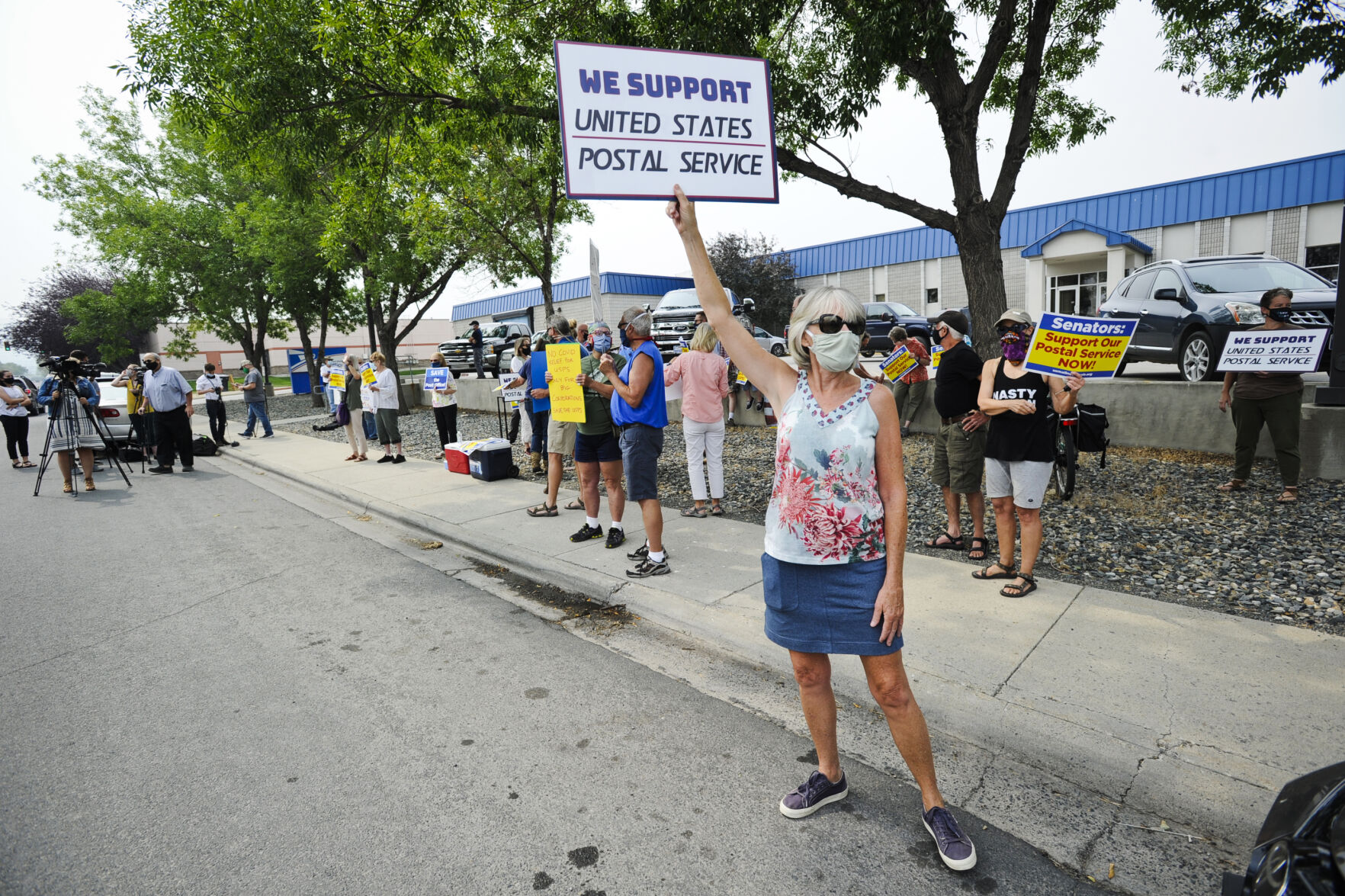 Joann McKinney holds a sign at a rally outside the U.S. Post Office in Helena on Tuesday.